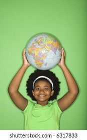 African American Girl Holding Globe On Top Of Head And Smiling At Viewer.