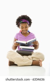 African American girl with large stack of books reading.