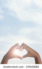 African American Girl Making Heart Shape With Hands Around Sun. 