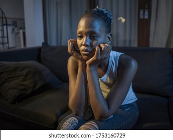 African American girl at night suffering depression - young attractive sad and depressed black woman lying thoughtful feeling sick on sofa couch in pain and worry 