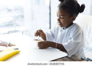 African american girl patient lying on bed eating in patient room at hospital. Hospital, childhood, medicine and healthcare, unaltered. - Powered by Shutterstock