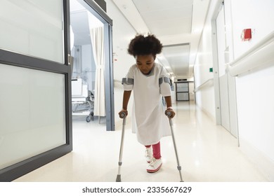 African american girl patient walking with crutches in corridor at hospital. Hospital, disability, childhood, medicine and healthcare, unaltered. - Powered by Shutterstock