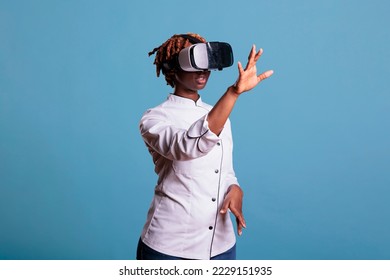 African american girl restaurant worker wearing virtual reality goggles to visualize online kitchen. Afro female chef with immersive multimedia viewer creating new recipes in cyberspace. - Powered by Shutterstock