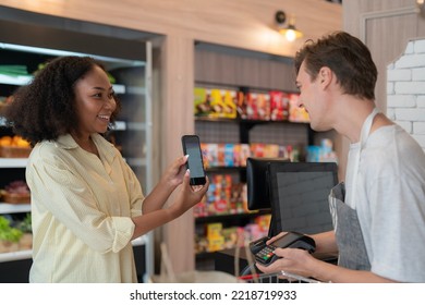 African american girl shopping in convenience store  on shelf in freezer in convenience store and pay money by barcode scan from mobile phone