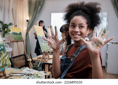 African American girl shows hand messed up with acrylic colors, joy, and fun learns with student children in art studio of an elementary classroom, creative painting with skills in school education.  - Powered by Shutterstock