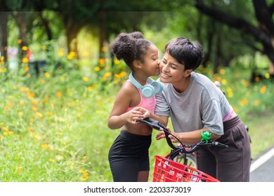 African American Girl Wearing Workout Clothes Happy Listening To Music On Headphones
Kiss  Asian Mothers Cycling In The Garden Together In The Park. Family Relax Concept.