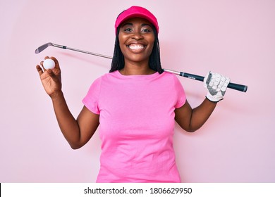 African american golfer woman with braids holding golf ball smiling with a happy and cool smile on face. showing teeth. 