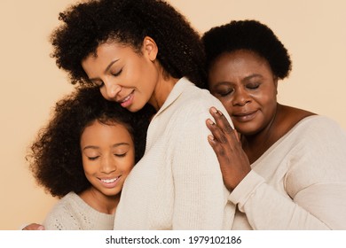 african american grandmother embracing with daughter and granddaughter with closed eyes isolated on beige