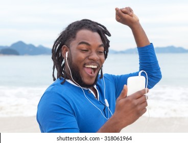 African american guy with dreadlocks listening to music at beach - Powered by Shutterstock