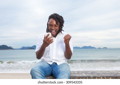 African American Guy With Dreadlocks And White Shirt Receiving Good News