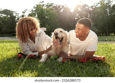 african american guy with girl lie together with golden retriever in the park in summer, young couple walks and plays with dog in nature, happy family with pet - Powered by Shutterstock