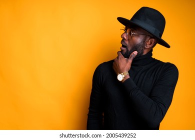 African American Guy With Glasses In A Hat And A Turtleneck Looking With Interest To The Side Wondering