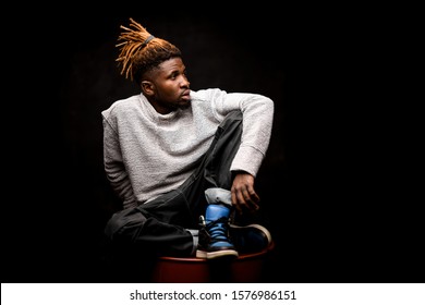 African american guy in streetwear sitting on a red barrel - Powered by Shutterstock