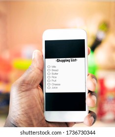A African American hand holding a phone displaying on the screen a typical grocery list