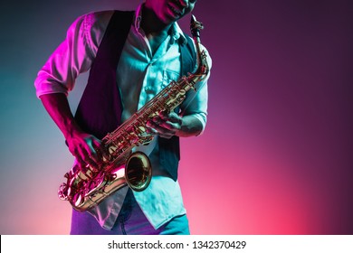 African American handsome jazz musician playing the saxophone in the studio on a neon background. Music concept. Young joyful attractive guy improvising. Close-up retro portrait. - Shutterstock ID 1342370429