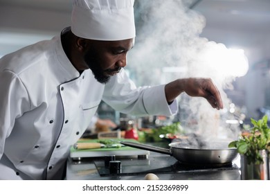 African american head cook garnishing gourmet dish with parmesan cheese while in restaurant kitchen. Culinary expert preparing dinner meal service while using fresh vegetables and herbs. - Shutterstock ID 2152369899