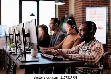 African american helpdesk receptionist with chronic impairment working at call center client care. Man wheelchair user giving telework assistance at customer service in disability friendly office.
