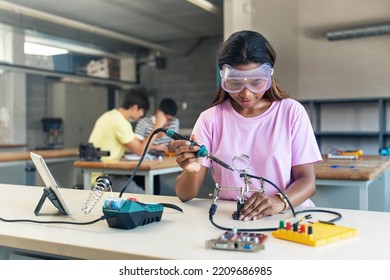 African American High School teenage Student wearing protective goggles soldering electronics circuit in the science technology workshop - Digital Innovation in Education - Powered by Shutterstock