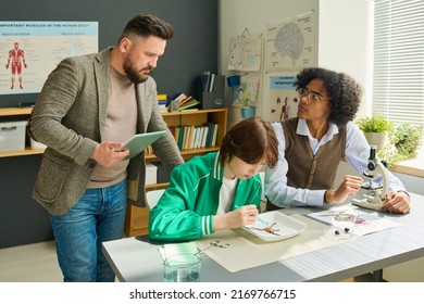 African American Highschool Student Looking At Teacher Of Anatomy While Studying Dissected Parts Of Frog In Microscope At Lesson