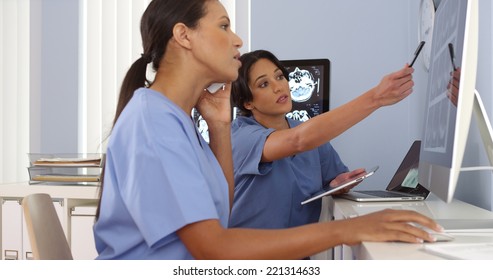 African American And Hispanic Doctors Working Together On Computers And Phone