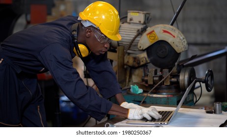 African American Industrial Engineer In Hard Hat Using Laptop Computer Video Conference Meeting In Industry Manufacturing Factory. Black Factory Worker Using A Notebook  With An Engineering Software