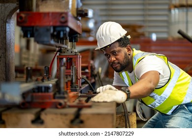 African American Industrial Worker Is Using Hydraulic Power Press Machine To Make Metal And Steel Part While Working Inside The Metal Sheet Galvanized Roof Factory For Safety Industry