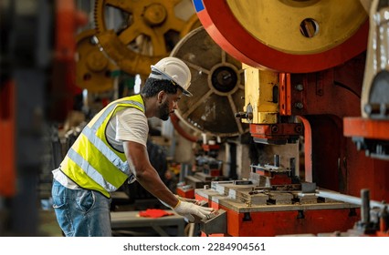 African American industrial worker is using hydraulic power press machine to make metal and steel part while working inside the metal sheet galvanized roof factory for safety industry - Powered by Shutterstock