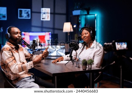 African American influencers in a cozy home studio, wearing headphones, engage their audience in an interesting online discussion. Black content providers recorded a vlog for social media platforms.