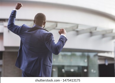 African american job seeker celebrating successful interview raising fists against business center, rear view with copy space - Powered by Shutterstock