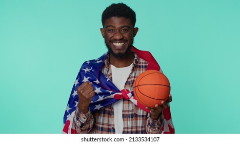 African American Joyful Young Man 20s Sportsman Basketball Fan In Checkered Shirt Holding American USA Flag Doing Winner Gesture Dancing Isolated On Blue Background. Workout Sport Motivation Lifestyle