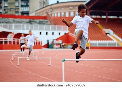 African American jumping over obstacles while running at the stadium. Copy space. - Powered by Shutterstock