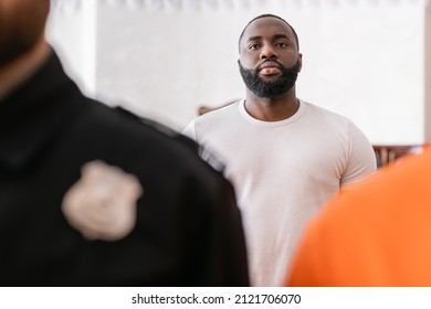 african american juryman standing near accused man and bailiff on blurred foreground