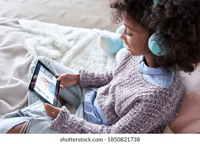 African american kid girl talking to grandmother or distance teacher during online virtual family chat videocall meeting on holiday by video conference call using tablet computer sitting on bed. - Powered by Shutterstock