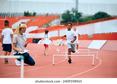 African American kid on running track with hurdles during sports training at the stadium. Copy space.  - Powered by Shutterstock