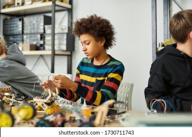 African American Kid At A Stem Robotics Class Making His Own Vehicle. Smart Children And STEM Education. Science And People Concept. Horizontal Shot. Selective Focus