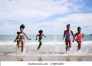 African American, Kids group in swimwear enjoying running to play the waves on beach. Ethnically diverse concept. Having fun after unlocking down from COVID 19. Summer holidays on beach with friends