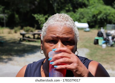 African American Lady Having Fun Having A Drink On The Outside With A Forestry Background