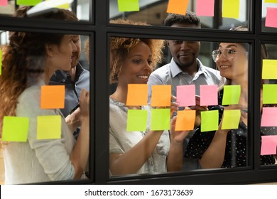 African American Leader With Diverse Employees Team Writing Creative Ideas, Tasks On Sticky Papers On Glass Scrum Board Close Up, Multiethnic Colleagues Discussing New Project Plan At Meeting