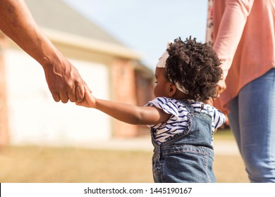 African American Little Girl Holding Hands With Her Parents.