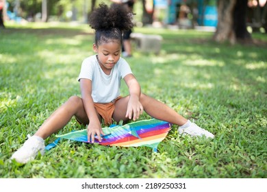 African American little girl preparing her kite to play in park on holiday in summer