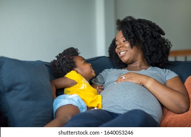 African American little girl talking with her￼ pregnant mother.
