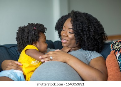 African American little girl talking with her pregnant mother.