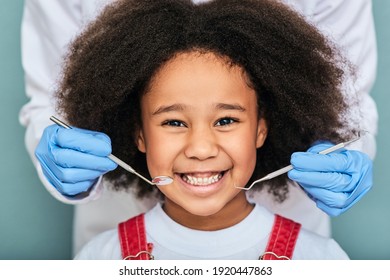 African American Little Girl With A Toothy Smile During An Inspection Of Oral Cavity By A Dentist. Child In A Dental Clinic For Children, Cropped