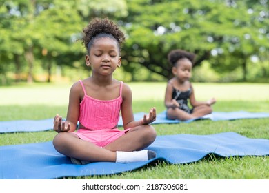 African American little girls sitting with closed eyes practicing meditate yoga on roll mat in the park. Kids afro girls with curly hair engaged training yoga in outdoor. - Powered by Shutterstock