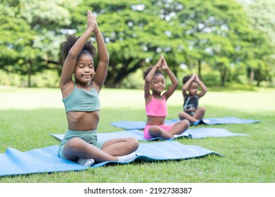 African American little girls sitting with closed eyes practicing meditate yoga on roll mat in the park. - Powered by Shutterstock