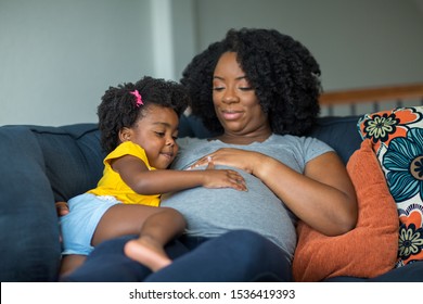 African American llittle girl holding her mother's stomach.