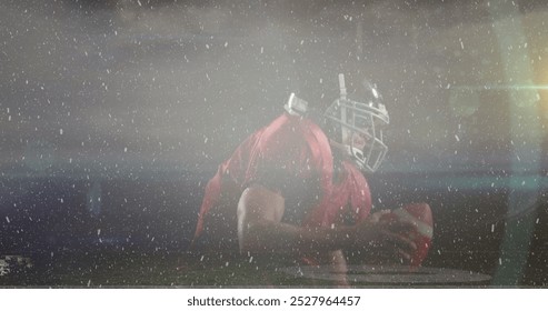 African American male athlete wearing football gear kneeling on field. He has short black hair, wearing red jersey and helmet, holding a football - Powered by Shutterstock