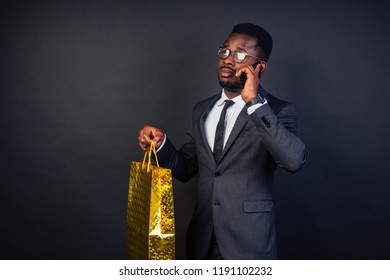 African American Male Business Partners Holding Shopping Bags On A Black Background In The Studio.black Friday Sale Seasonal Concept