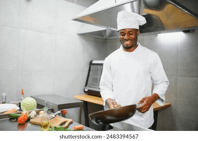 African American male chef frying vegetables in restaurant kitchen. - Powered by Shutterstock