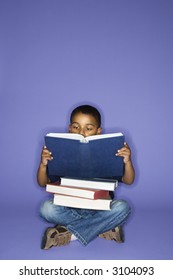 African American male child sitting with books.